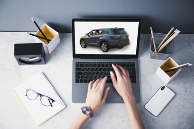 Buying online. Woman choosing car using laptop, top view