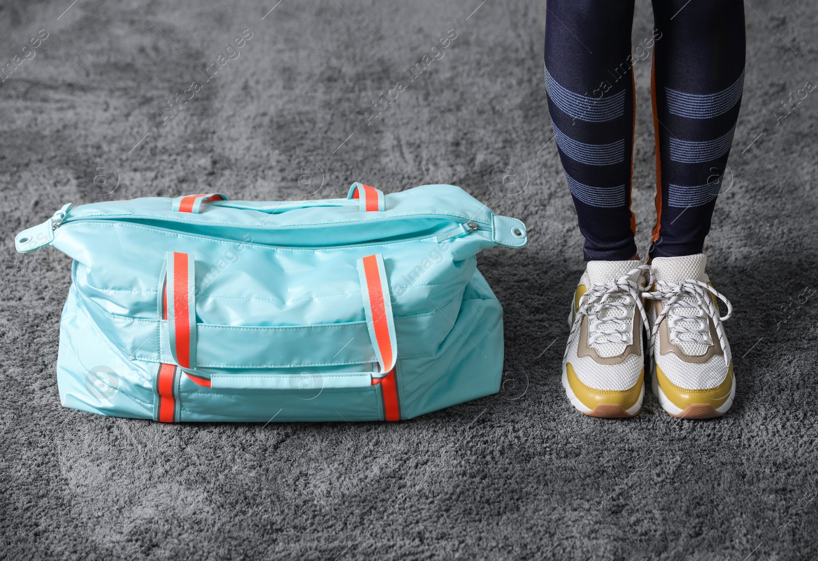 Photo of Woman with sportive bag on grey carpet, closeup