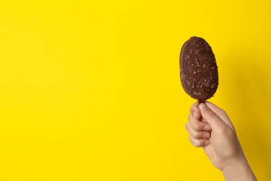 Photo of Woman holding delicious ice cream with chocolate against color background, space for text