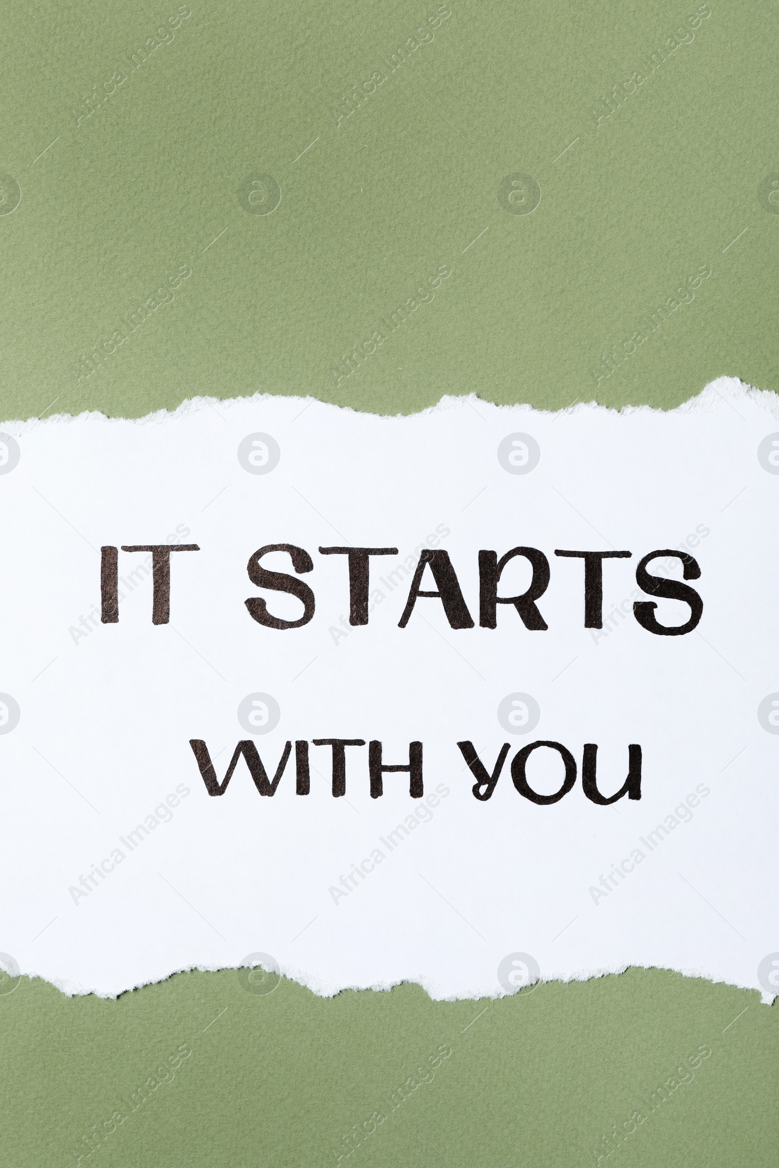 Photo of Sheet of paper with phrase It Starts With You on green background, top view