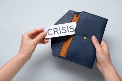 Photo of Woman holding paper sheet with word Crisis and purse on white background, above view