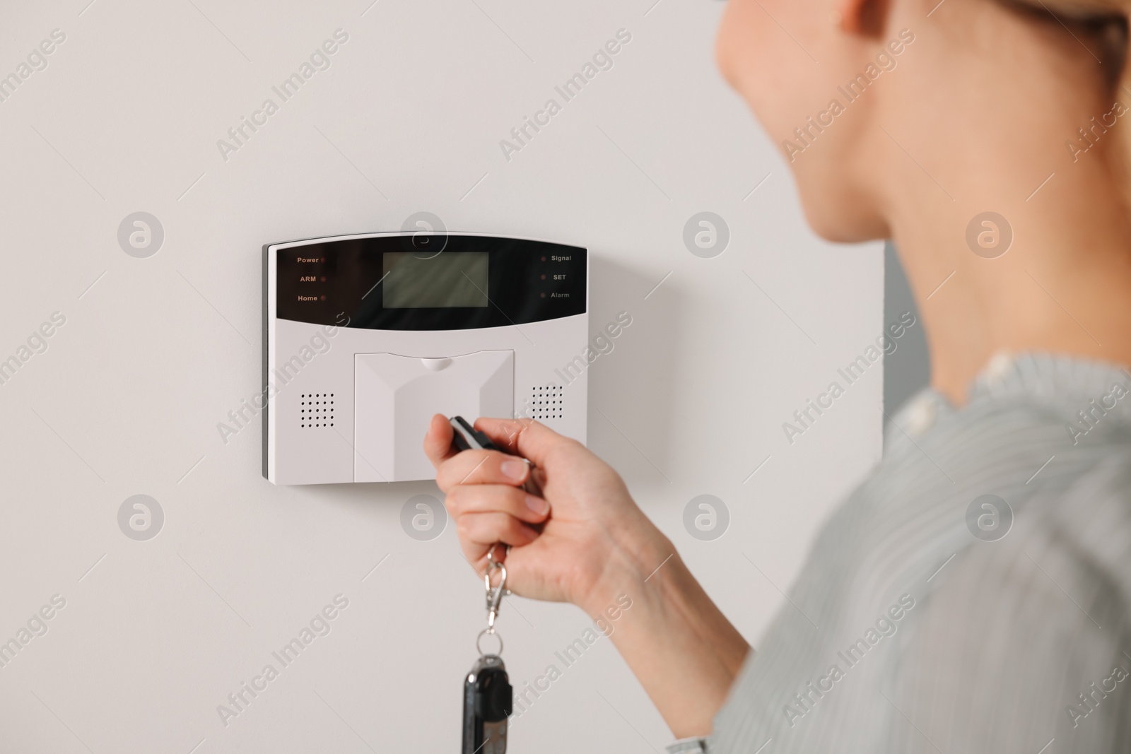 Photo of Home security system. Woman using alarm key fob, closeup