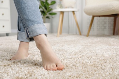 Photo of Woman standing on soft carpet at home, closeup. Space for text