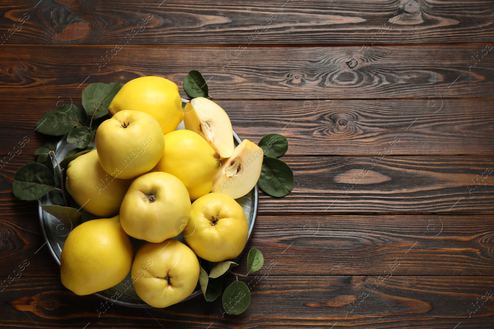 Photo of Fresh ripe organic quinces with leaves on wooden table, top view. Space for text