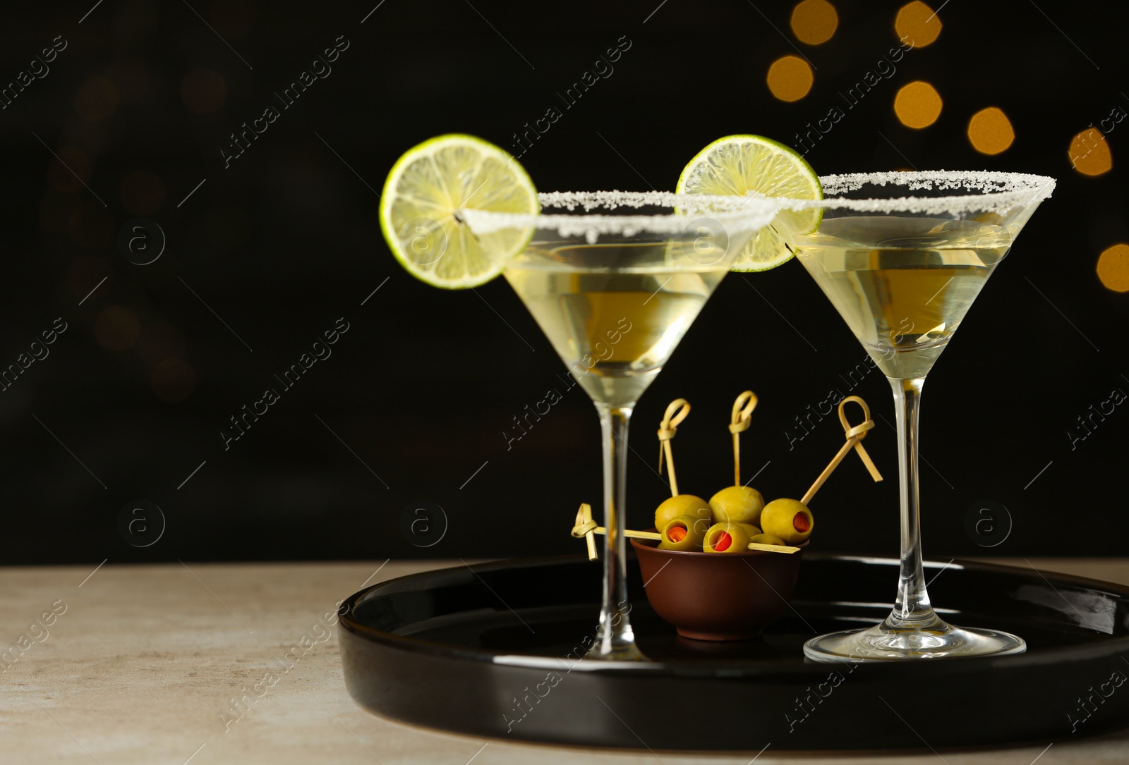 Photo of Glasses of Lime Drop Martini cocktail on grey table against blurred background
