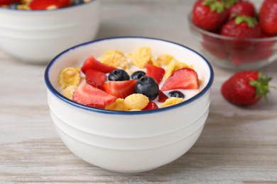 Bowl of tasty crispy corn flakes with milk and berries on wooden table, closeup