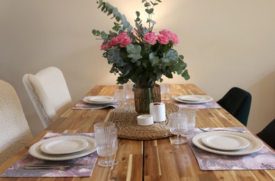 Beautiful table setting with bouquet and candles indoors. Roses and eucalyptus branches in vase