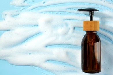 Photo of Bottle with cleansing foam on light blue background, top view. Cosmetic product