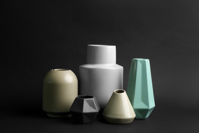 Stylish empty ceramic vases on black background