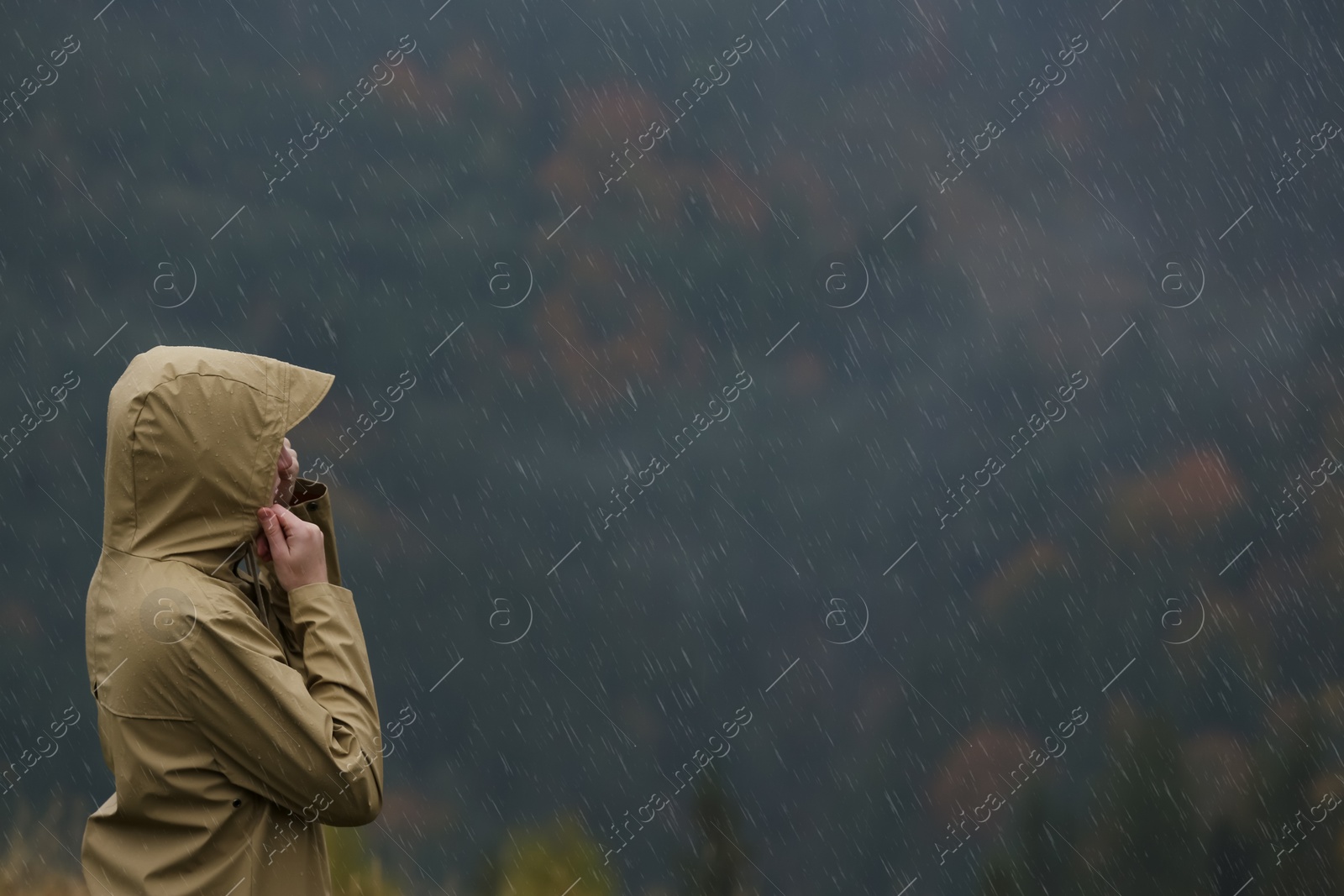 Photo of Woman in raincoat enjoying mountain landscape under rain, space for text