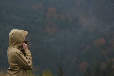 Photo of Woman in raincoat enjoying mountain landscape under rain, space for text