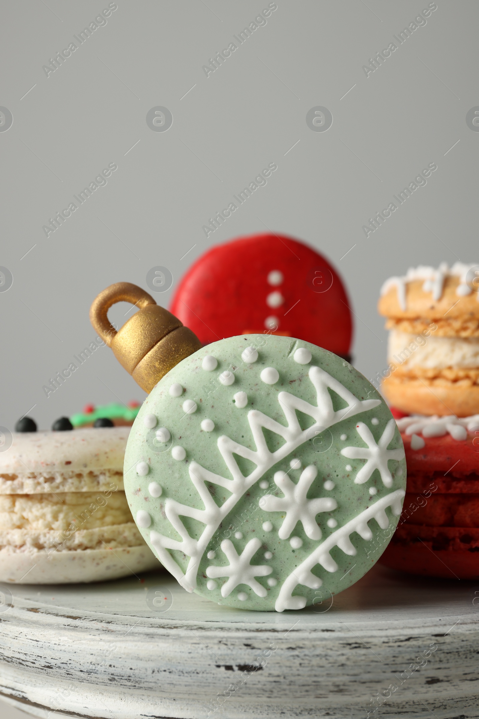 Photo of Beautifully decorated Christmas macarons on stand against light grey background, closeup