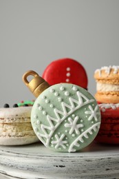 Photo of Beautifully decorated Christmas macarons on stand against light grey background, closeup
