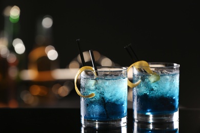 Glasses of fresh alcoholic cocktails on bar counter, space for text