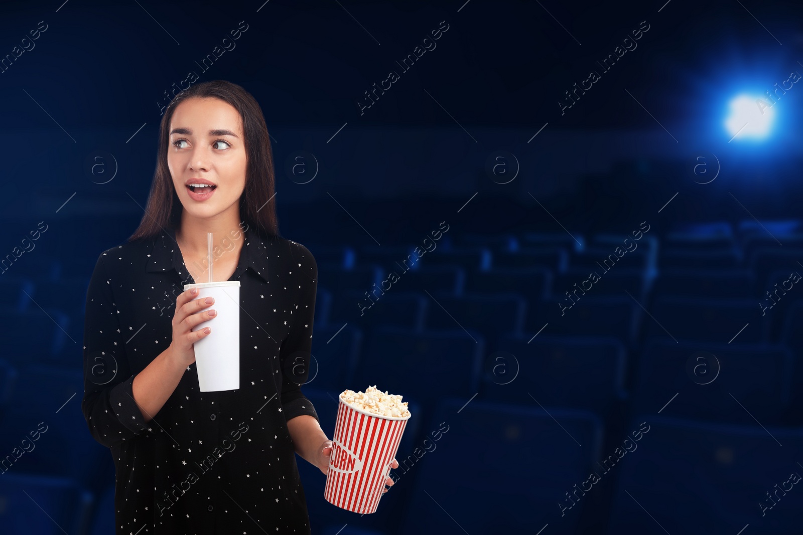 Image of Emotional woman with popcorn and beverage in cinema, space for text