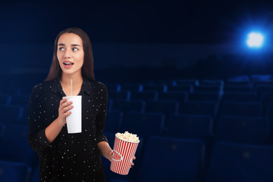 Image of Emotional woman with popcorn and beverage in cinema, space for text