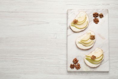 Delicious bruschettas with ricotta cheese, pears and walnuts on white wooden table, top view. Space for text