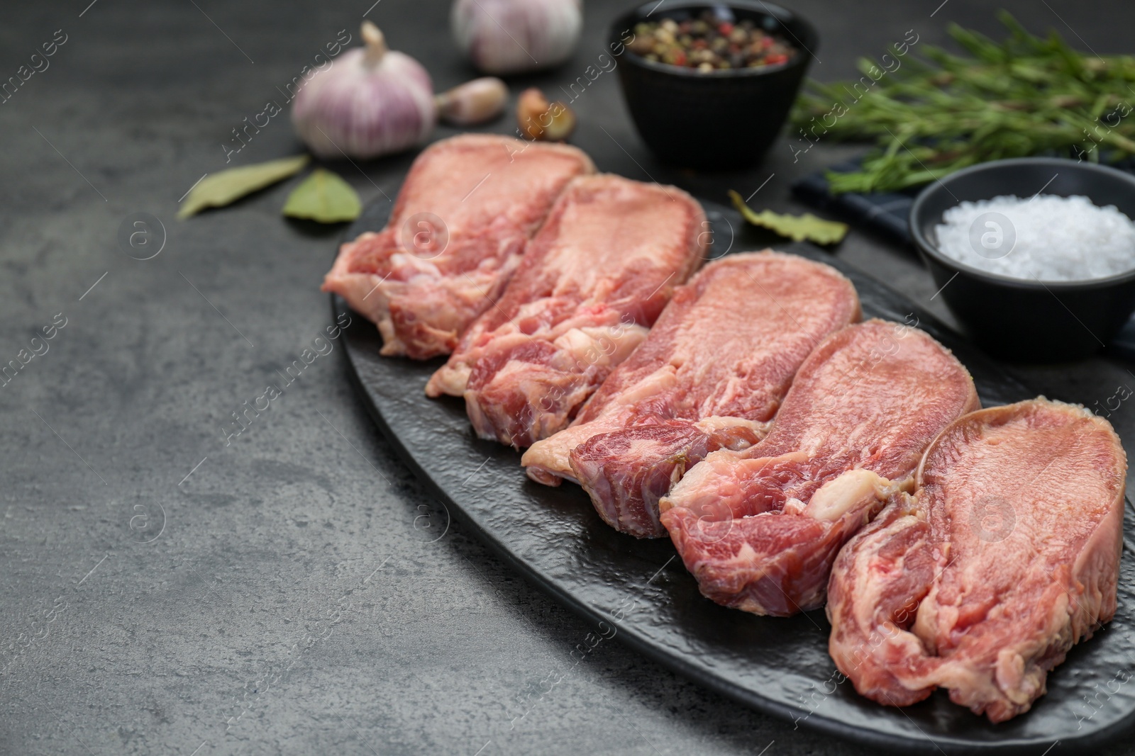 Photo of Raw beef tongue pieces on grey table, space for text