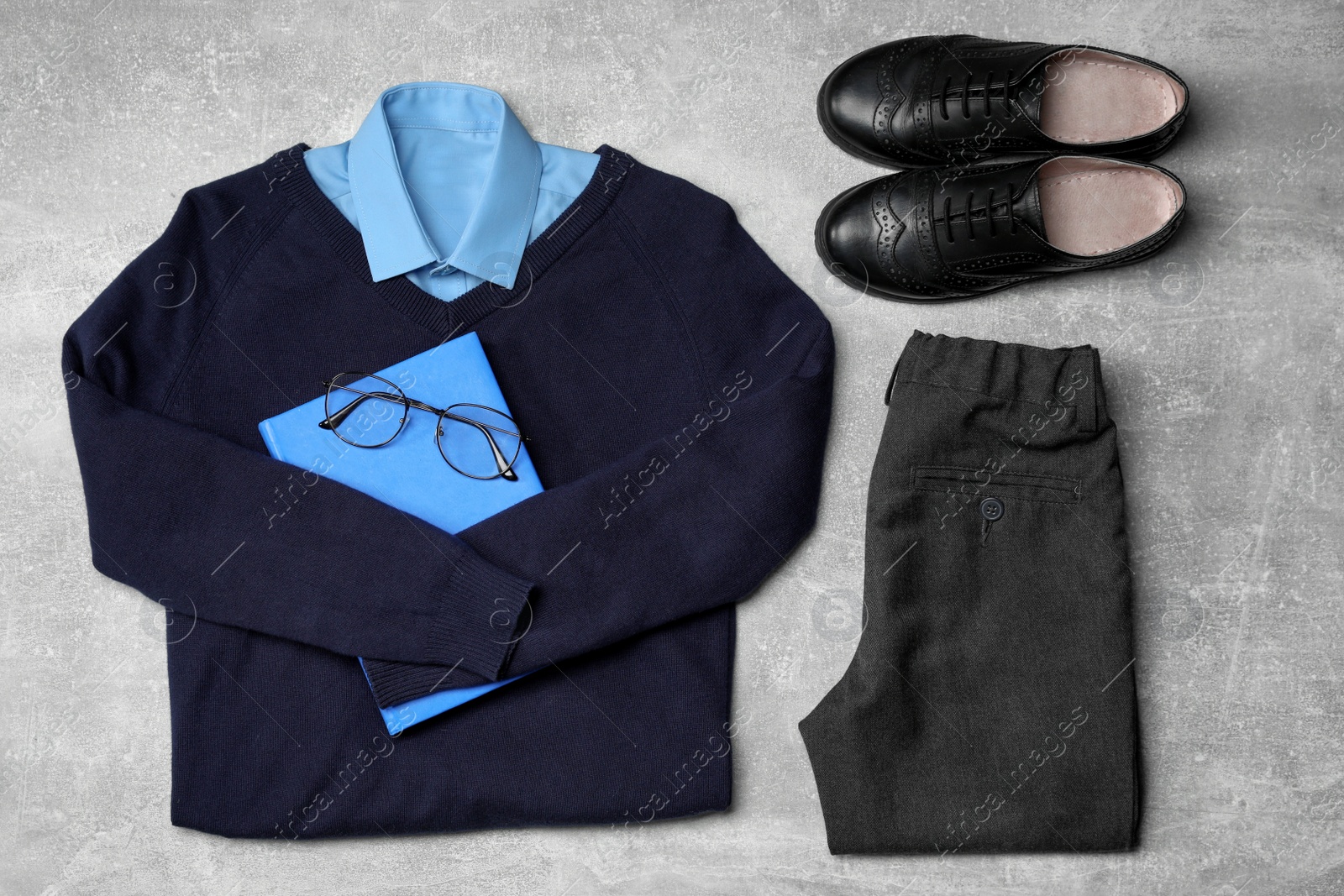 Photo of Stylish school uniform for boy, glasses and notebook on grey background, flat lay