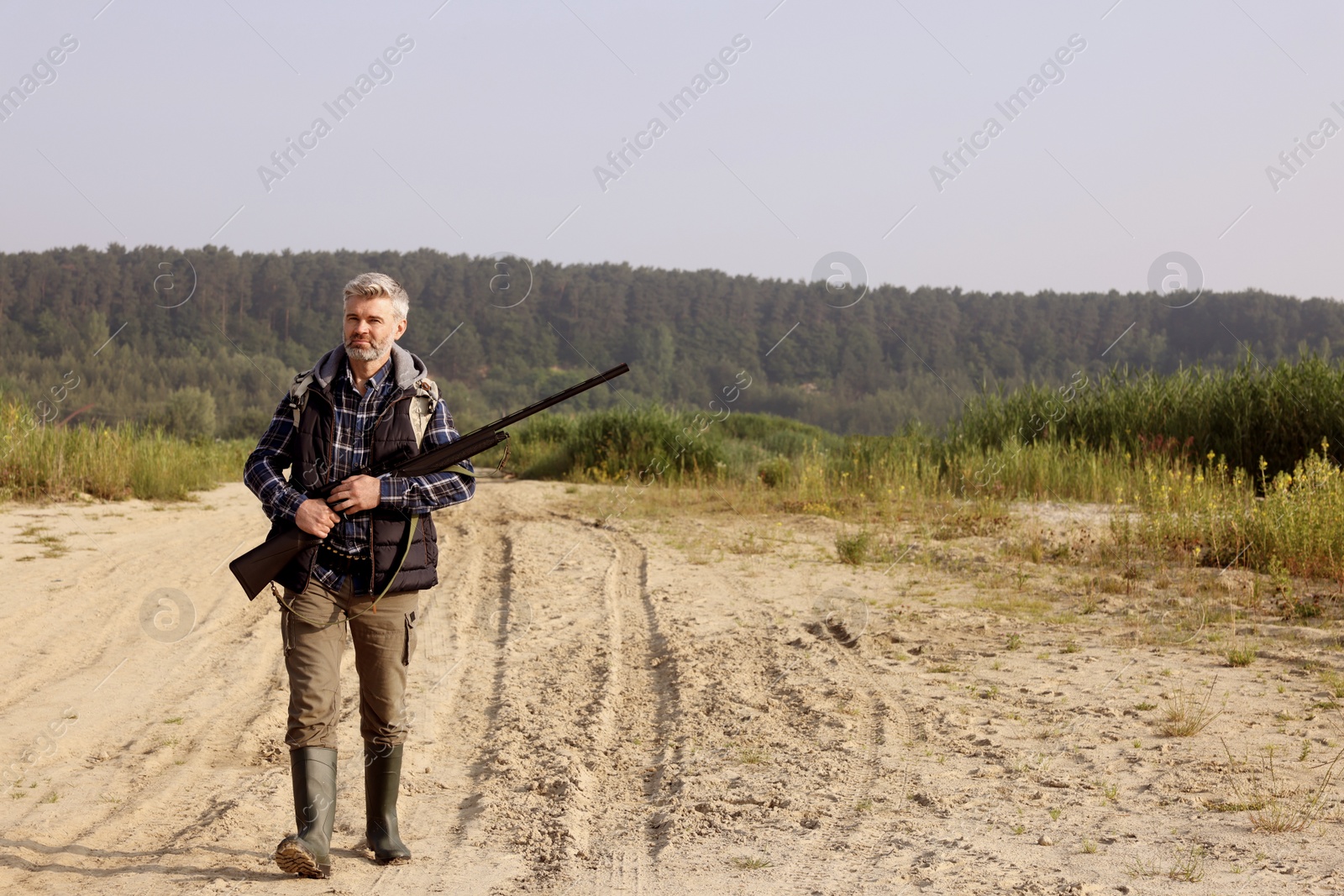 Photo of Man with hunting rifle outdoors. Space for text