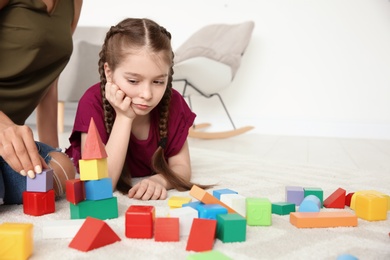 Photo of Young woman and little girl with autistic disorder playing at home