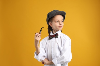 Photo of Cute little detective with smoking pipe on yellow background