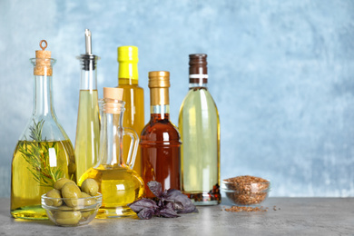 Photo of Different cooking oils in bottles on grey table