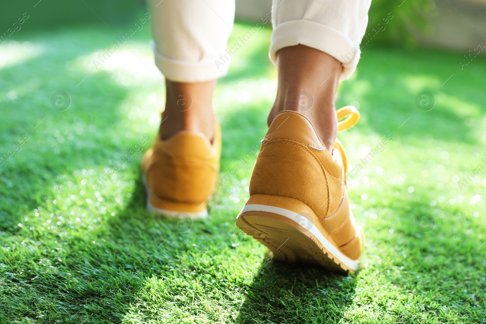 Photo of Young woman wearing stylish sneakers on green grass, closeup