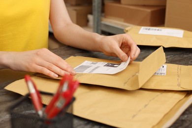 Post office worker sticking barcode on parcel at counter indoors, closeup