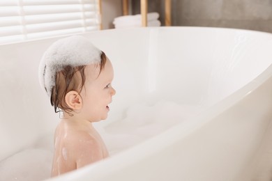 Cute little baby bathing in tub at home. Space for text