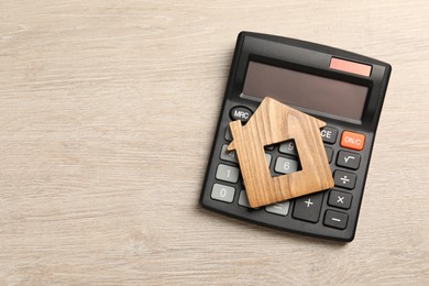 Mortgage concept. House model and calculator on wooden table, top view with space for text