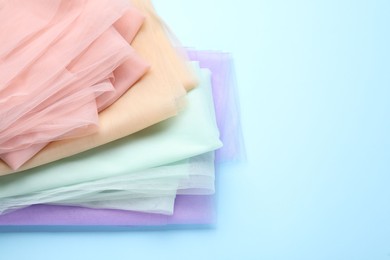 Beautiful colorful tulle fabrics on turquoise background. Space for text