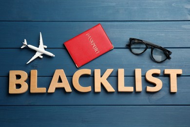 Photo of Word Blacklist of letters, toy airplane and passport on blue wooden background, flat lay