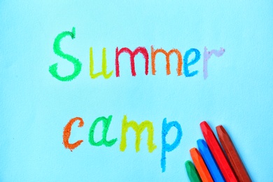 Photo of Crayons and words SUMMER CAMP on color background, top view