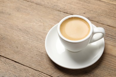 Photo of Aromatic coffee in cup on wooden table. Space for text