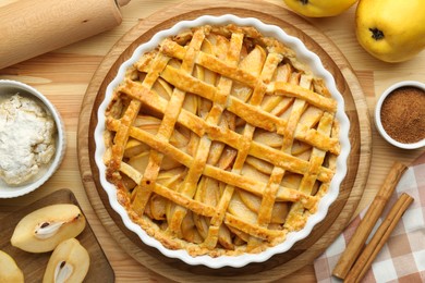 Photo of Tasty homemade quince pie and ingredients on wooden table, flat lay