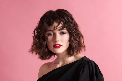 Portrait of beautiful young woman with wavy hairstyle on pink background