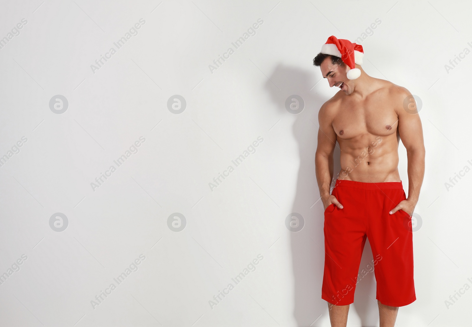 Photo of Sexy shirtless Santa Claus on light background, space for text