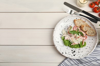 Photo of Plate of delicious vegetable salad dressed with mayonnaise and croutons served on white wooden table, flat lay. Space for text