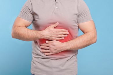 Image of Man suffering from stomach pain on light blue background, closeup