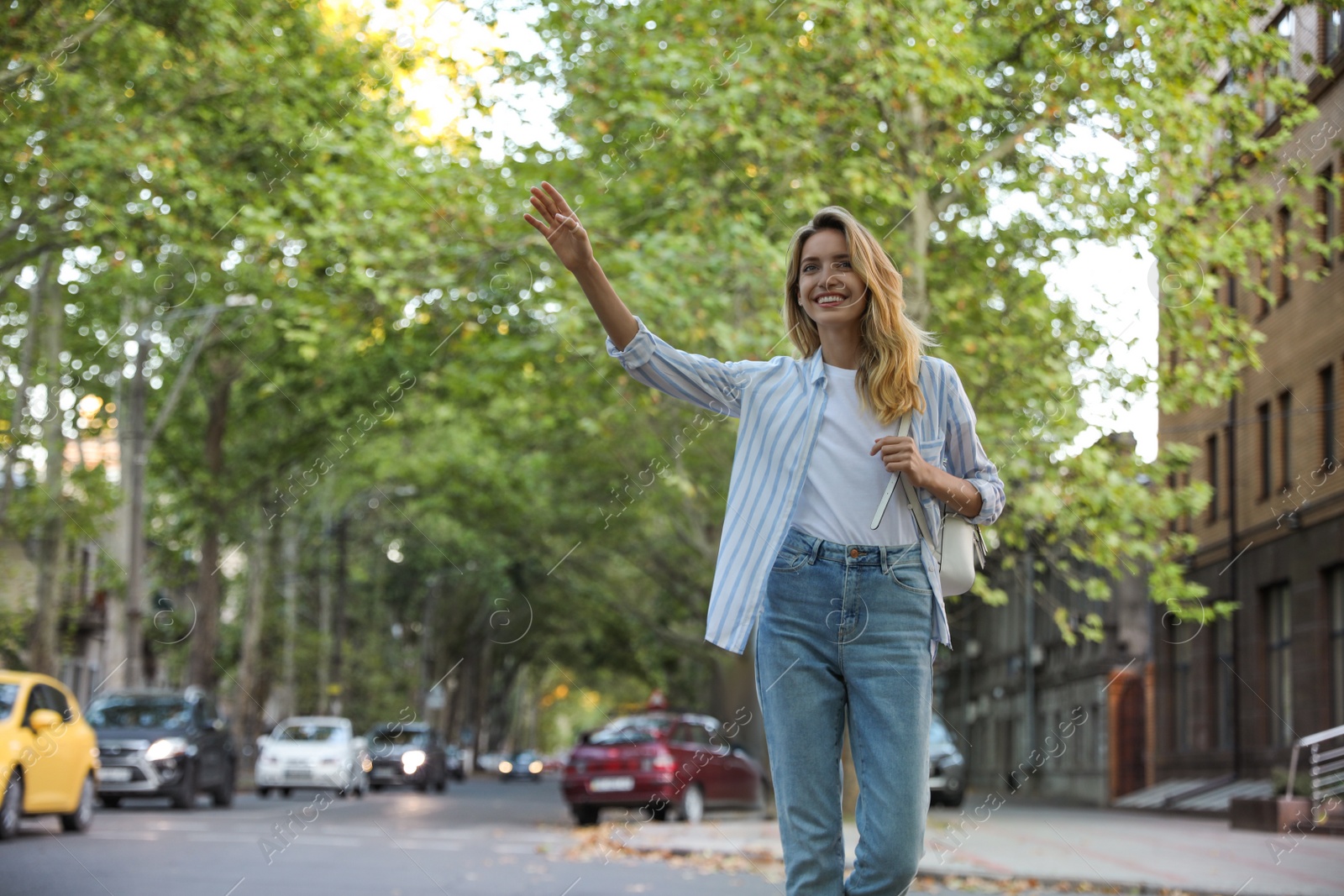 Photo of Young woman catching taxi on city street