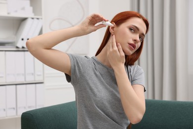 Photo of Woman applying medical ear drops at home