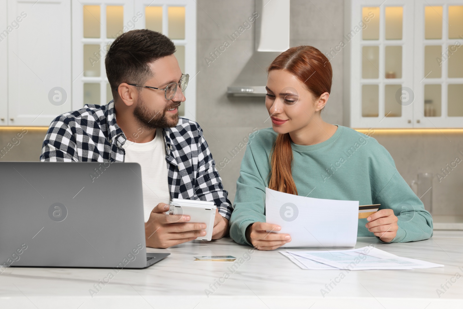 Photo of Couple calculating taxes for online payment at table in kitchen