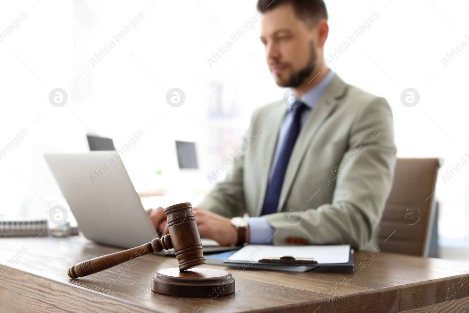 Photo of Gavel on table and lawyer working with laptop in office