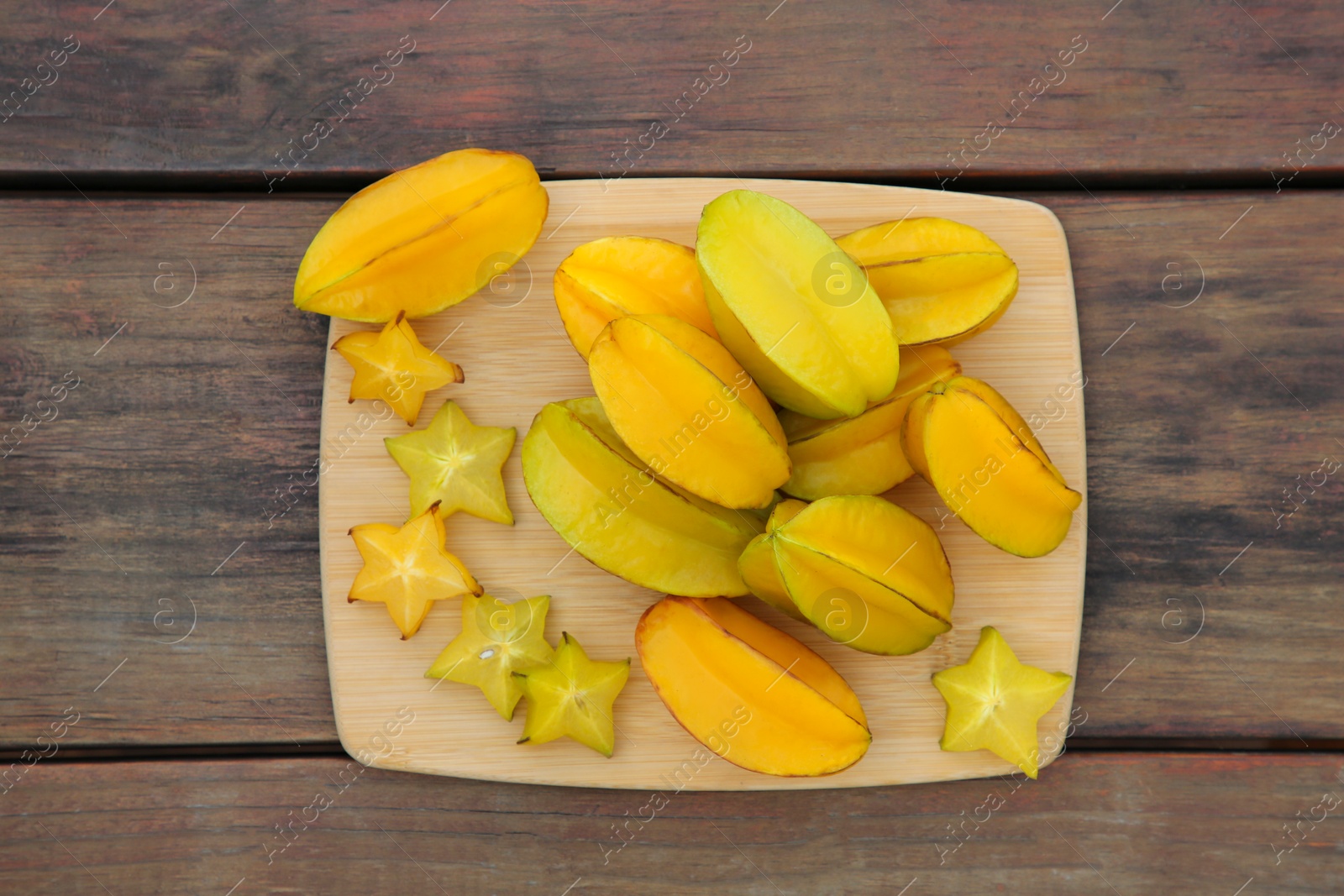 Photo of Cut and whole delicious ripe carambolas on wooden table, top view