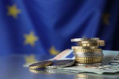 Photo of Coins and banknotes on table against European Union flag, space for text