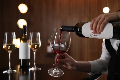 Photo of Waitress pouring wine into glass in restaurant, closeup