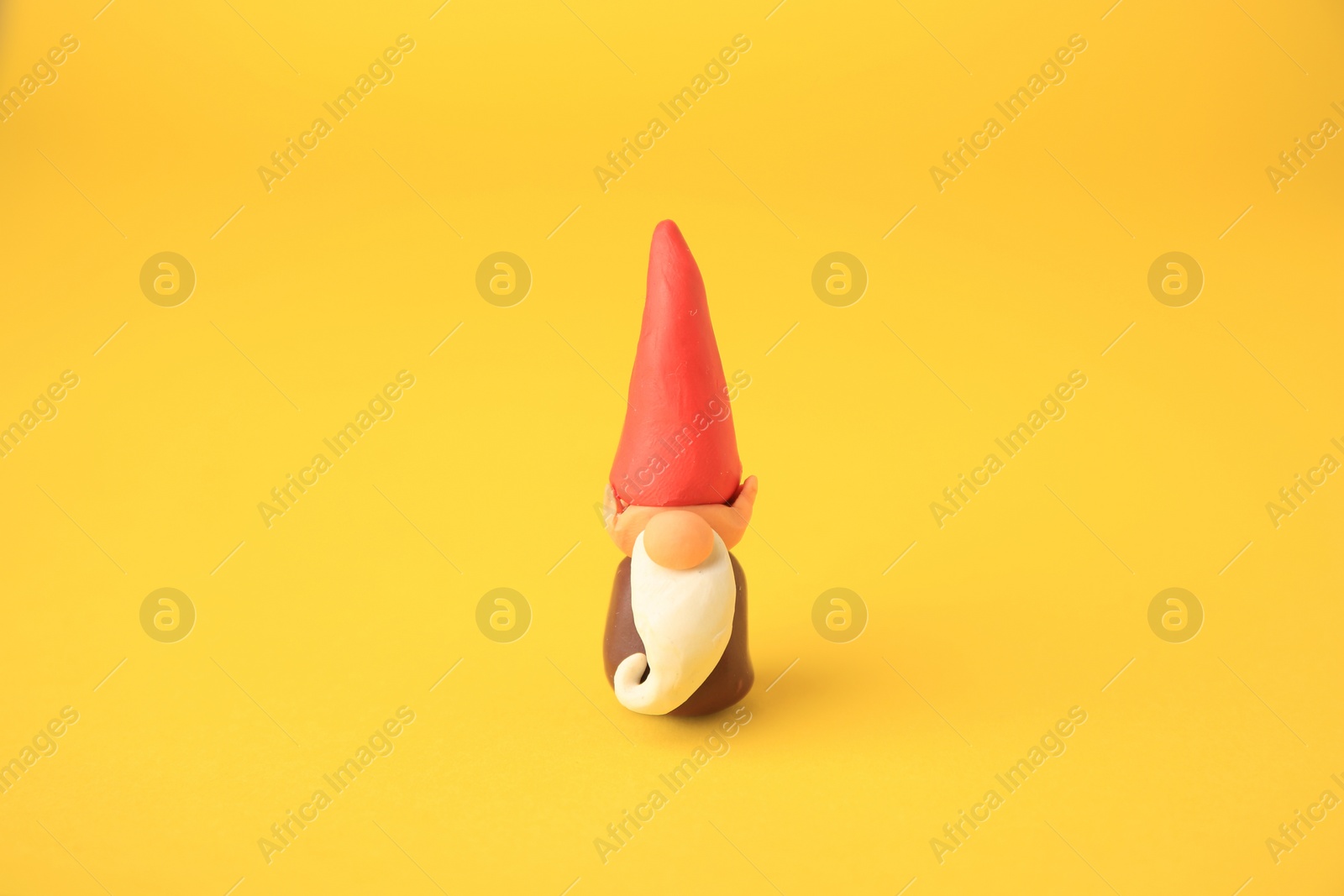 Photo of Dwarf made from plasticine on yellow background. Children's handmade ideas