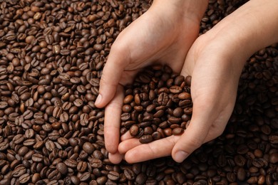 Woman with roasted coffee beans, closeup. Space for text