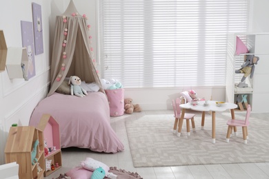 Photo of Cute child's room interior with toys and modern furniture